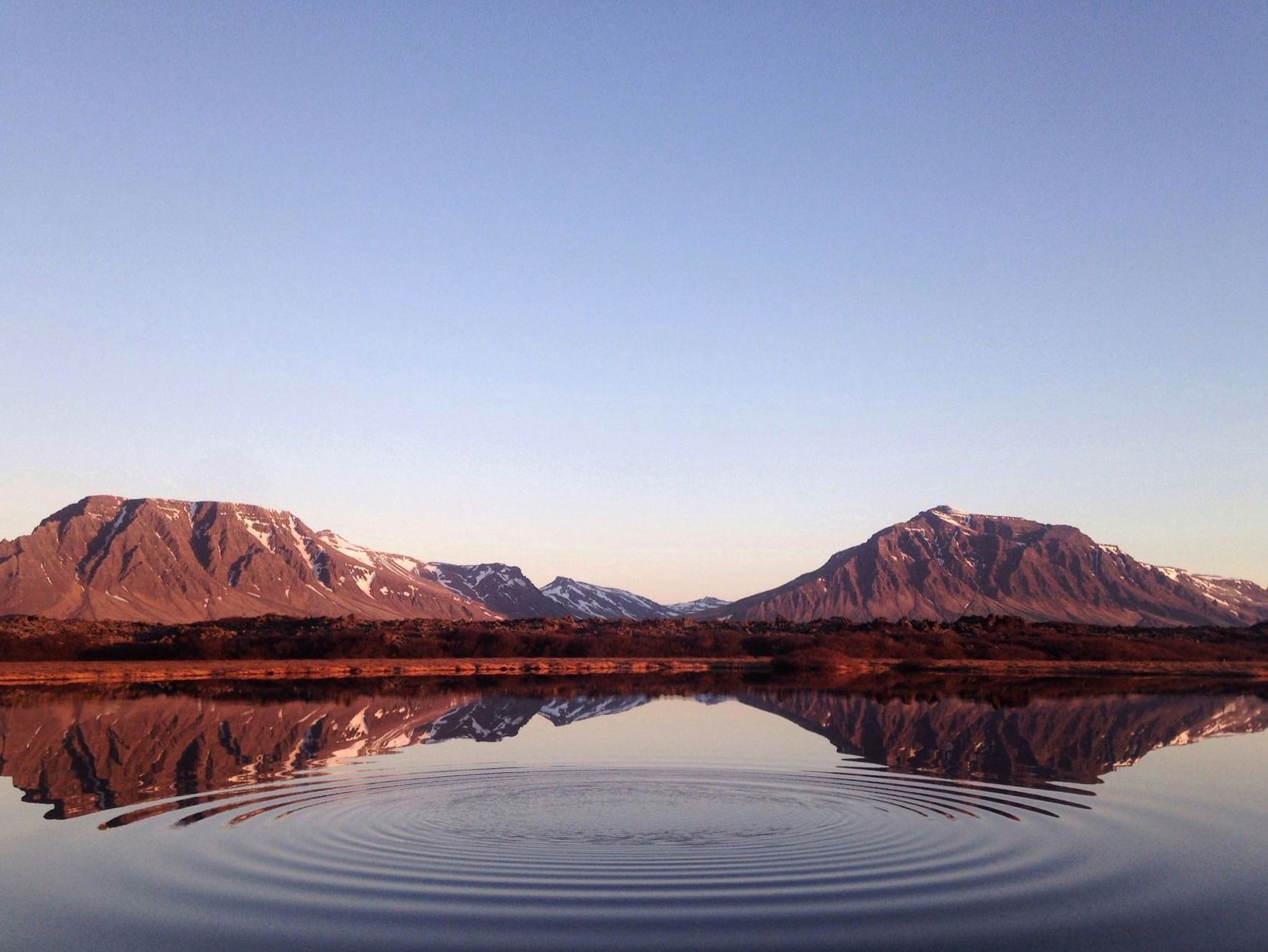 Traveller looking across an expansive New Zealand lake and mountains